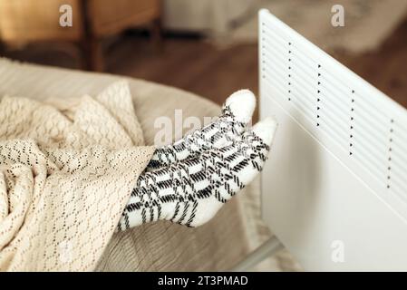 pieds féminins en chaussettes, devant le chauffage électrique en gros plan. saison de chauffage froid. Photo de haute qualité Banque D'Images