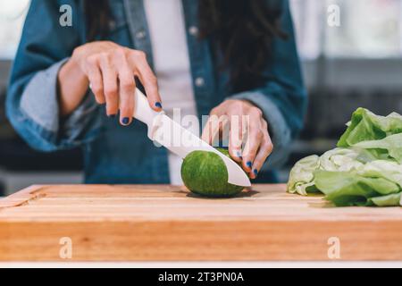 Gros plan d'une femme coupant un légume dans sa cuisine Banque D'Images