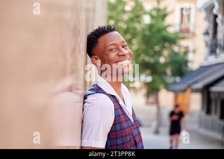 bel homme afro-américain montrant des dents blanches appuyées contre le mur Banque D'Images