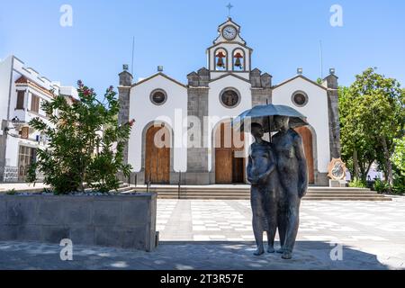 Valleseco, Espagne - 8 septembre 2022 : Sculpture appelée « couple avec parapluie » par Félix Reyes Arencibia devant l’église de San Vicente Ferrer, i. Banque D'Images
