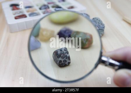 Quelques pierres semi-précieuses à travers une loupe tenue par une main caucasienne Banque D'Images