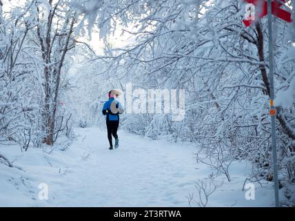Kiruna, Suède- 02 décembre 2022 : une fille qui court sur le chemin sauvage couvert de neige en hiver Abisko National Park Banque D'Images