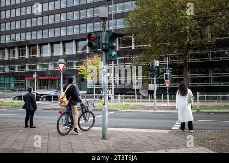 Photo d'un homme à vélo, attendant de traverser une rue où les voitures roulent à Dusseldorf, en Allemagne. Banque D'Images