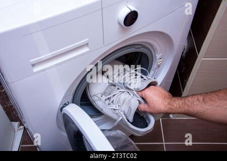 Vue de dessus de mettre de vieilles baskets sales dans la machine à laver Banque D'Images