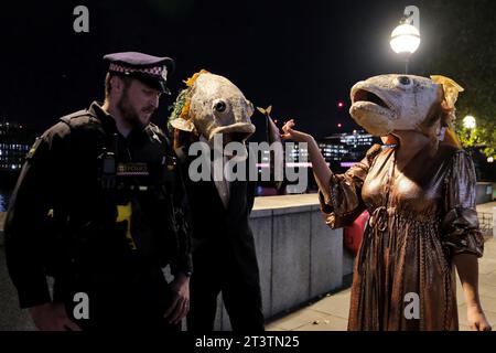 Londres, Royaume-Uni. 26 octobre 2023. Des militants du groupe environnemental Ocean Rebellion ont organisé une manifestation devant le Fishmongers' Hall où se déroulait la cérémonie annuelle de remise des prix du Marine Stewardship Council (MSC). Les militants portant des masques à tête de saumon suggèrent que des pratiques cruelles se produisent dans les fermes certifiées RSPCA à plus haut niveau de bien-être, où plusieurs rapports écrits par des organisations environnementales, présentent des preuves de surpeuplement, de mauvais traitements, de maladies et d'infestations de poux parmi les stocks de poissons. Crédit : Photographie de onzième heure / Alamy Live News Banque D'Images