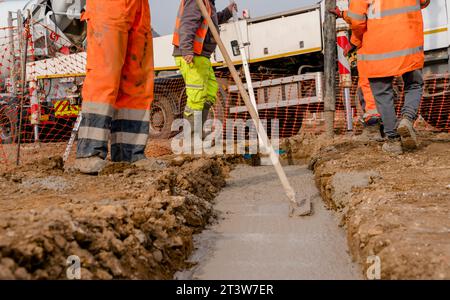 Pompe à béton mobile sur le chantier de construction utilisée par les constructeurs versant la fondation de maison avec du béton prêt à l'emploi humide Banque D'Images