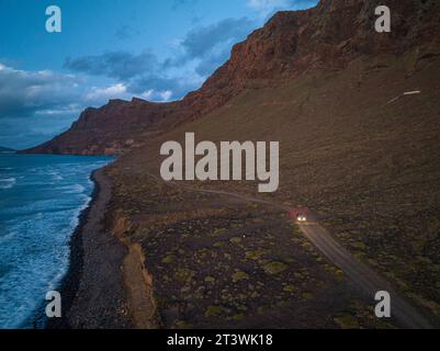 Une perspective aérienne révèle la beauté cachée d'un chemin de terre serpentant le long du littoral accidenté. Banque D'Images