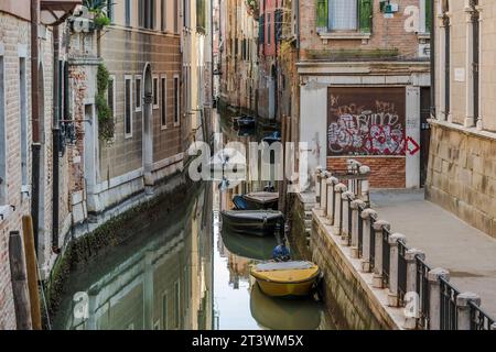 Petits bateaux garés dans un canal typique au coeur de Venise, en Italie Banque D'Images