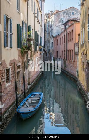 Petits bateaux garés dans un canal typique au coeur de Venise, en Italie Banque D'Images