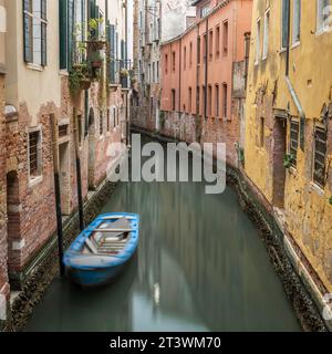 Petits bateaux garés dans un canal typique au coeur de Venise, en Italie Banque D'Images