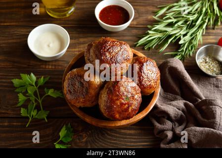 Côtelettes maison de viande hachée dans un bol sur une table en bois. Gros plan Banque D'Images