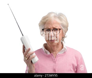 Frustrée femme âgée utilisant un vieux téléphone sans fil, elle regarde l'appareil photo déçu Banque D'Images