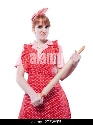 Femme au foyer agressive de style vintage tenant un rouleau à pâtisserie et regardant la caméra Banque D'Images