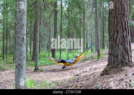 Un homme, touriste, se relaxant dans un hamac dans une forêt en Estonie, profitant de la randonnée et du camping dans la nature sauvage estonienne, Estonie, Europe Banque D'Images