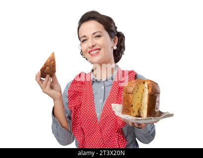 Vintage femme tablier en mangeant une tranche de panettone italien traditionnel, pâtisserie maison Banque D'Images