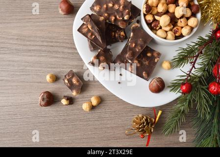 Chocolat aux noisettes et fruits secs dans une assiette blanche sur une table en bois décorée élément décoratif de noël. Vue de dessus. Banque D'Images