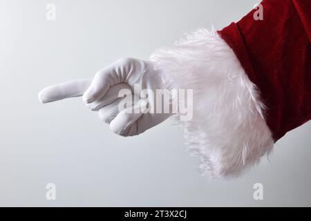 Main du Père noël avec gant blanc et costume traditionnel rouge faisant geste pour pointer avec l'index avec fond dégradé blanc. Banque D'Images