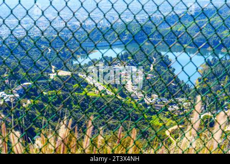 Hollywood Reservoir, ses environs pittoresques et la ville tentaculaire de Los Angeles capturée depuis un point de vue au sommet d'une colline à travers une clôture en treillis métallique. Banque D'Images