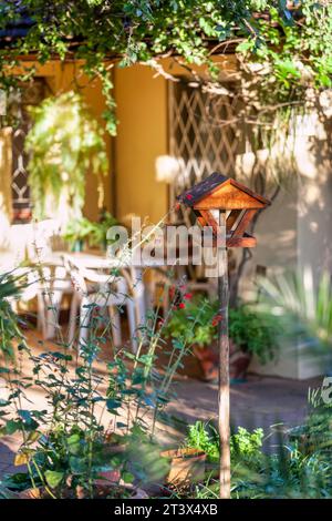 birdhouse dans un jardin confortable dans la cour arrière, table et chaises en arrière-plan sur le patio Banque D'Images