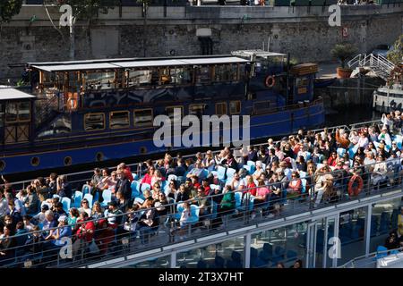 Un bateau rempli de touristes navigue le long de la Seine, Paris. Banque D'Images