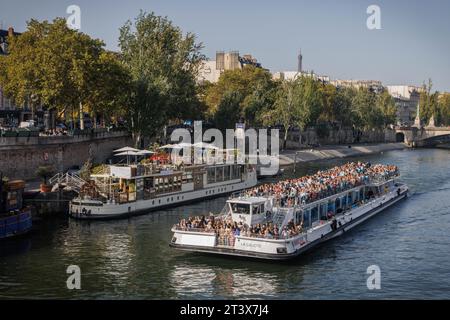 Un bateau rempli de touristes navigue le long de la Seine, Paris. Banque D'Images