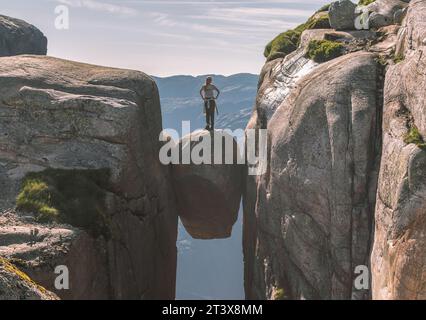 Courageuse jeune femme voyageur debout sur Kjeragbolten Banque D'Images