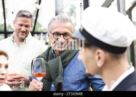 Famille souriante et amis avec des boissons à l'arrière-cour pendant la fête Banque D'Images