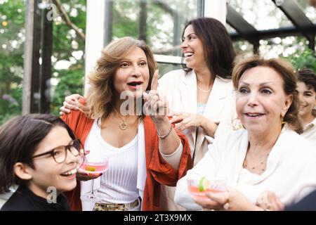 Les femmes et les garçons heureux appréciant la fête d'été à la cour arrière Banque D'Images