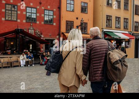 Vue arrière d'un couple de touristes senior se tenant la main tout en marchant ensemble dans la ville Banque D'Images