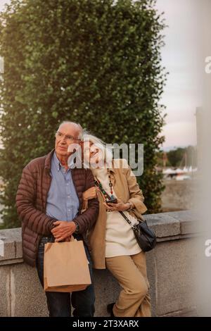 Couple senior attentionné se penchant sur la rampe tout en regardant loin Banque D'Images