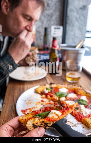 La pizza napolitaine Margherita se trouve sur une table en bois rustique dans une pizzeria traditionnelle. Banque D'Images