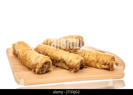 Plusieurs morceaux de baklava doux sur une planche de cuisine en bois, macro, isolé sur fond blanc. Banque D'Images