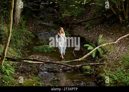 Femme marchant le long des eaux fraîches d'un ruisseau en Angleterre, Grande-Bretagne, Royaume-Uni. Banque D'Images