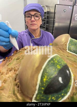 La chocolatière Donna Oluban apporte la touche finale à un présentoir d'Halloween avec un crapaud effrayant aux feuilles d'automne, une baguette et des livres de sorts faits de chocolat au Cadbury World de Birmingham. La création détaillée de 90 cm de haut, comprenant 50 kilogrammes de chocolat, a été conçue pour être «aussi fantaisiste que possible sans être trop effrayante» pour les visiteurs de l'attraction de Birmingham. Date de la photo : mercredi 25 octobre 2023. Banque D'Images