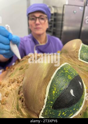 La chocolatière Donna Oluban apporte la touche finale à un présentoir d'Halloween avec un crapaud effrayant aux feuilles d'automne, une baguette et des livres de sorts faits de chocolat au Cadbury World de Birmingham. La création détaillée de 90 cm de haut, comprenant 50 kilogrammes de chocolat, a été conçue pour être «aussi fantaisiste que possible sans être trop effrayante» pour les visiteurs de l'attraction de Birmingham. Date de la photo : mercredi 25 octobre 2023. Banque D'Images