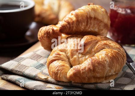 Gros plan de deux croissants avec conserves de fraises et tasse de café Banque D'Images