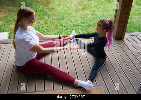 Jolie mère et fille faisant des exercices d'étirement assis sur le plancher en bois Banque D'Images