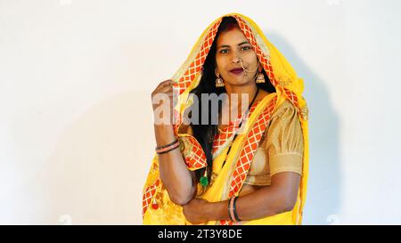 Belle femme indienne portant du saree jaune et souriant à la caméra à l'occasion de Karwa Chauth. Banque D'Images