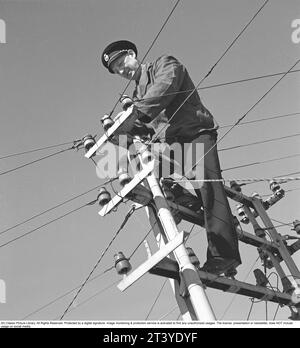 Dans les années 1940 Un homme est vu grimper au sommet d'un poteau électrique avec des fils et des câbles d'alimentation allant dans des directions différentes. Une sorte d'entretien ou de réparation des connecteurs ou des isolateurs. Suède 1942 Kristoffersson ref H29-2 Banque D'Images