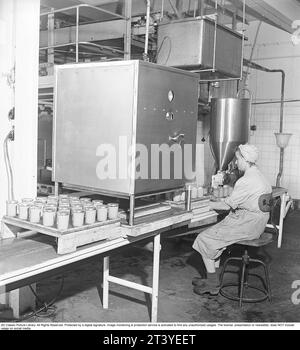 Emplois dans les années 1940 Intérieur des usines de la société alimentaire Winborg où une employée siège à la ligne de production de nourriture dans des bocaux en verre. Suède 1949. Kristoffersson réf AM1-4 Banque D'Images