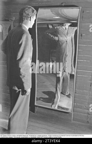 Åke Ödmark , 1916-1994 , sauteur en hauteur suédois et détenteur du record suédois de saut en hauteur dans les années 1939-1946 avec une hauteur de 2 mètres. Honoré avec le badge Big Boys n°98. Ici à Skrattkammaren à Gröna Lund, où il se voit dans un miroir riant. Les miroirs ordinaires ont une surface plane, tandis que ce miroir est incurvé à la fois vers l'intérieur et vers l'extérieur, concave et convexe. Le miroir fait paraître grand et mince. D'autres miroirs courts et épais. Gröna Lund Stockholm Suède juillet 1940. Kristoffersson ref 153-10 Banque D'Images
