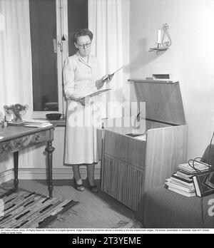 Femme au gramophone dans les années 1940 Dagmar Lange, auteur suédois, 1914-1991. Détenant deux disques en pensant qu'elle jouera sur le gramophone. Sur ce modèle, il y avait des moyens de modifier le son afin d'améliorer l'expérience d'écoute. Les disques étaient faits d'un matériau fragile et la vitesse du disque à sonner comme il se doit était de 78 tours par minute. Suède 1949. Kristoffersson réf. AT17-3 Banque D'Images