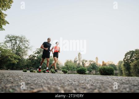 Couple jogging à travers le parc en vêtements de sport. Banque D'Images