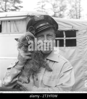 Dans les années 1950 Un homme photographié avec son petit chien qu'il est visiblement aime et tient près. Il fume un cigare et porte une casquette. Suède 1951. Kristoffersson réf BP30-6 Banque D'Images