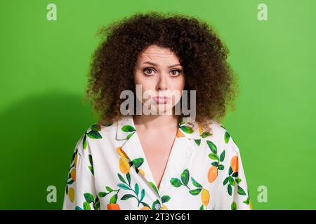 Photo de triste fille déprimée habillée chemise imprimée pourchassant les lèvres pouting ayant des problèmes isolé fond de couleur verte Banque D'Images