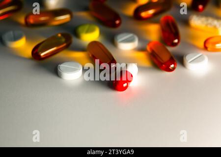 Gros plan des comprimés transparents et des pilules colorées dans la brillance à travers la lumière latérale. Fond de l'espace de copie isolé des médicaments pharmaceutiques Banque D'Images