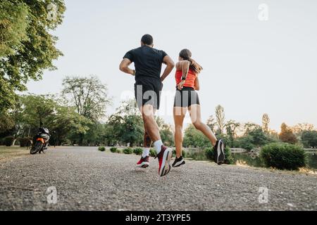 Deux coureurs en forme de jogging dans le parc, entraînement à l'extérieur. Couple sportif s'exerçant ensemble. Banque D'Images