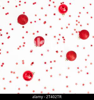 Motif de Noël en décoration de boules rouges avec confettis sur blanc. Fond festif. Pose à plat, vue de dessus Banque D'Images