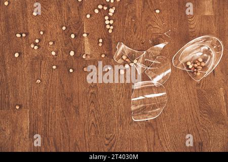 Fragments d'un verre transparent cassé sous la compote avec des raisins secs. Des morceaux de verre brisé reposent sur le sol avec de l'espace pour copier. Photo de haute qualité Banque D'Images