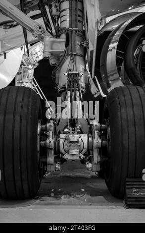 Gros plan du train d'atterrissage d'un avion stationné et soutenu à l'intérieur du hangar. Photo noir et blanc. Banque D'Images